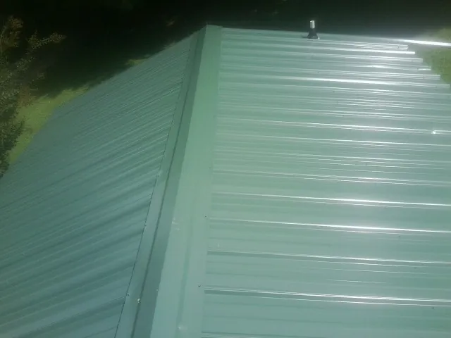 New green metal panels meeting at the ridge of a roof — Flat Roof Repair work by our crew in Crabtree