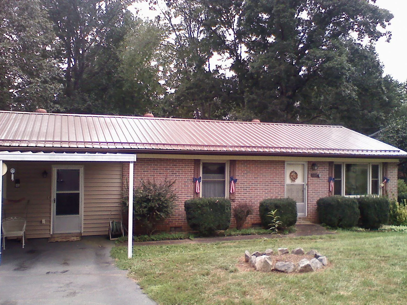 Bronze metal roof and carport on a brick ranch home — Roof Repair work by our crew in Crabtree
