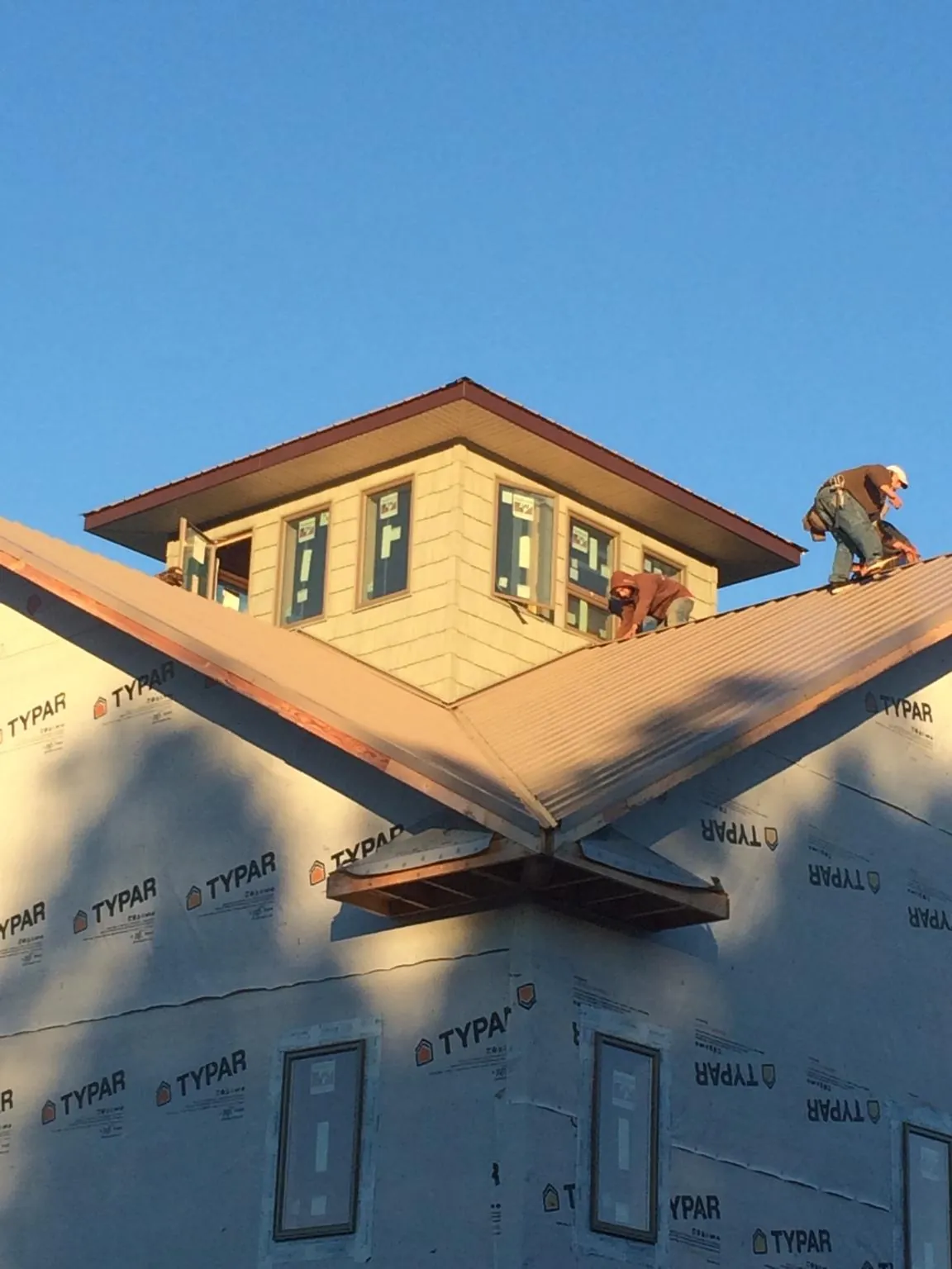 Roofers working around a rooftop cupola on a new metal roof at sunset — Roof Waterproofing in Crabtree by Roofing Brothers